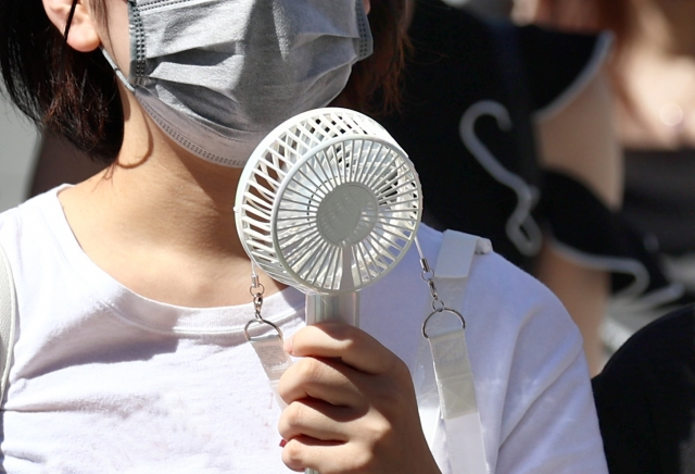 une dame prend un petit ventilateur